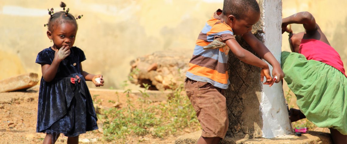 This picture shows three children at the village tap. One of them is drinking directly from the tap