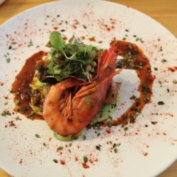 This picture shows a plate of food with a large succulent prawn on top.