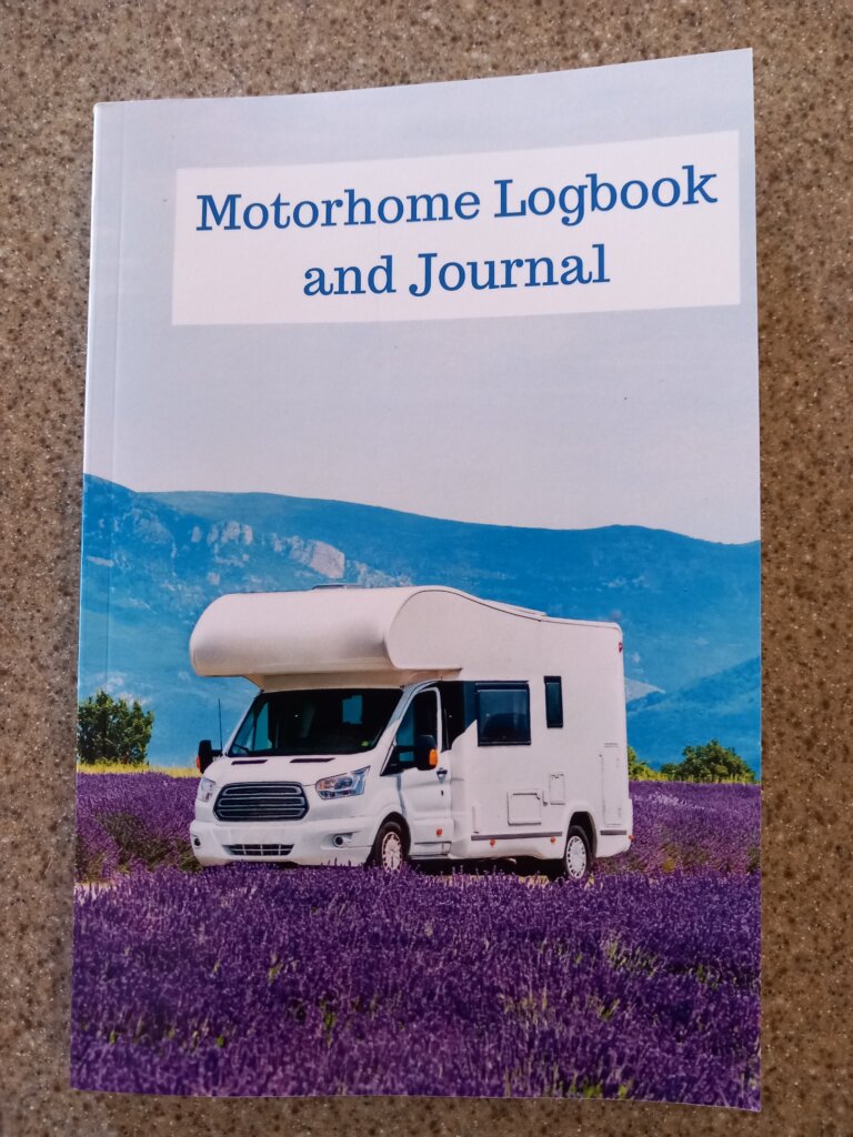 This photo shows the front cover of my motorhome logbook. It is a white motorhome parked in a field of vibrant lavender