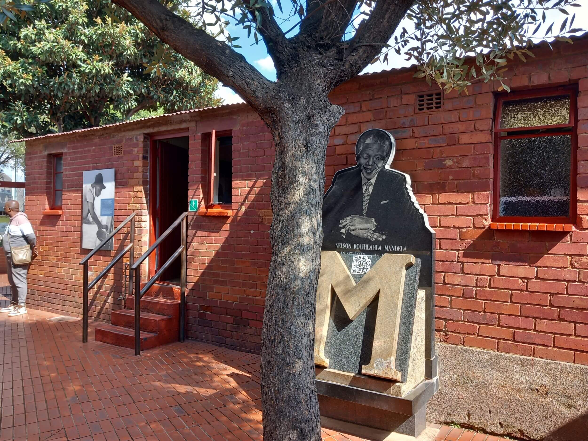 This image shows the front of Nelson Mandela's restored house with a full-size image of him welcoming you inside