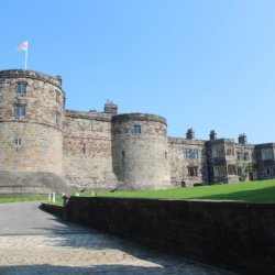 This photo shows the imressive main part of Skipton Castle with lush green lawns in the foreground