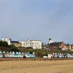 This photo shows an expanse of sandy beach with beach huts in the distance